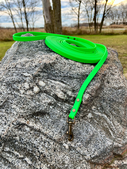 A durable neon green biothane dog long lead with contrasting antique hardware, designed for strength and style, ideal for everyday use and outdoor adventures. Great for training recall and the beginning steps of off leash dog training.